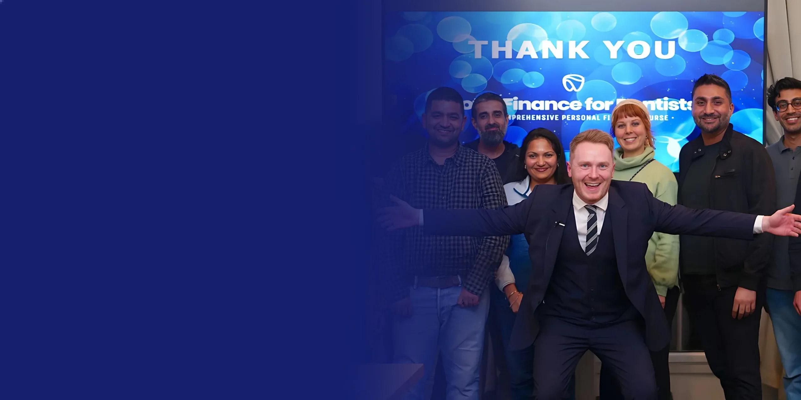 A group of smiling professionals with Dr. James Martin spreading his arms in front of a ‘Finance for Dentists’ presentation with a blue gradient on the left hand side.