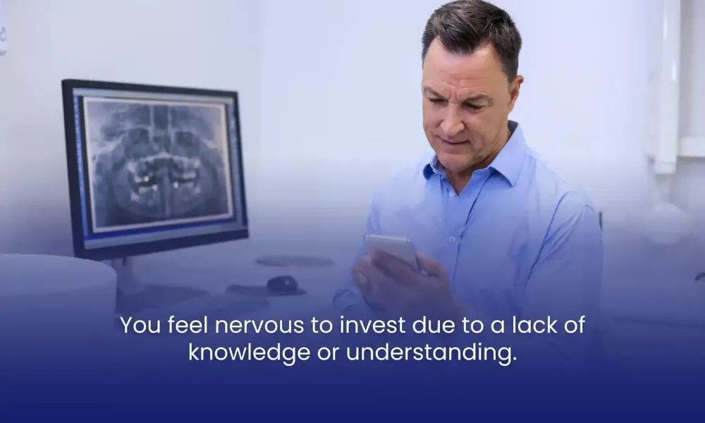 Man in blue shirt looking at phone, with an X-ray on the monitor behind and text overlay about investment fears.