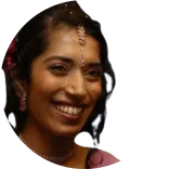 Dr Arti Shah, a dentist based in the UK, smiling warmly, wearing traditional jewellery on her forehead and earrings, with her hair styled and decorated.