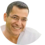 A headshot of Dr Max Al-Nakib, a dentist in the UK, wearing glasses and happily smiling.