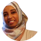 Dr Deena Mo, a dentist in the UK, is wearing beige clothing and a printed hijab while smiling.